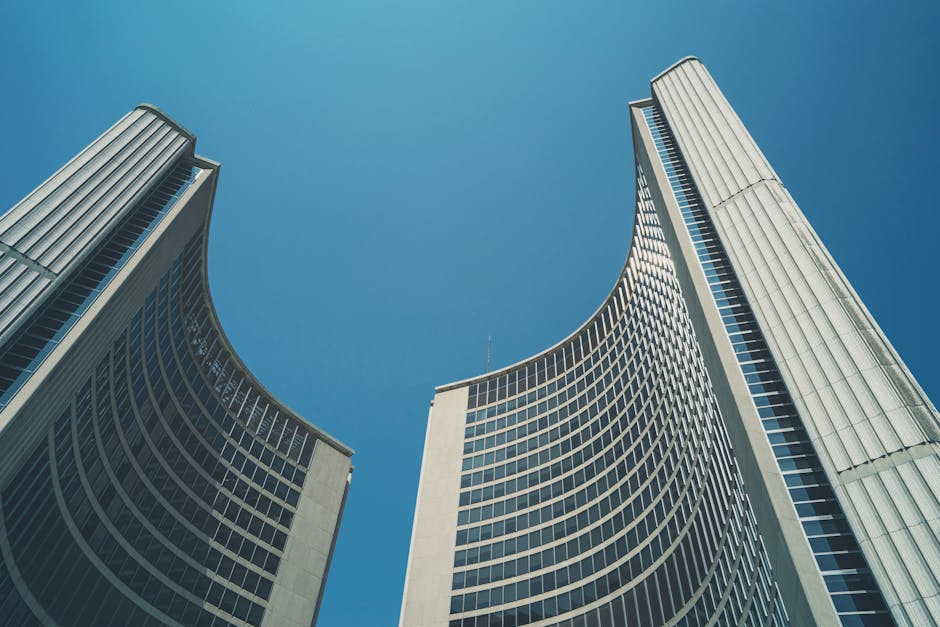 Striking architectural shot of Toronto City Hall's iconic curved buildings against a clear blue sky.